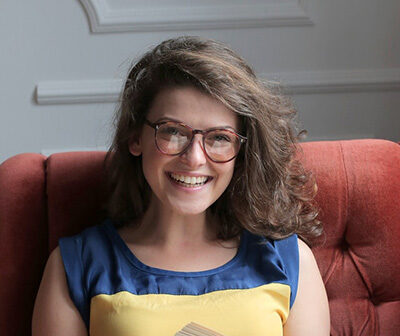 woman in blue and yellow dress sitting on red sofa